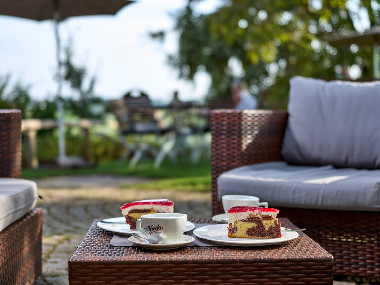 Zwei Korbstühle und ein Tisch mit Kaffee und Kuchen im Biergarten des Golf- und Landhotels Anetseder im Bayerischen Wald.