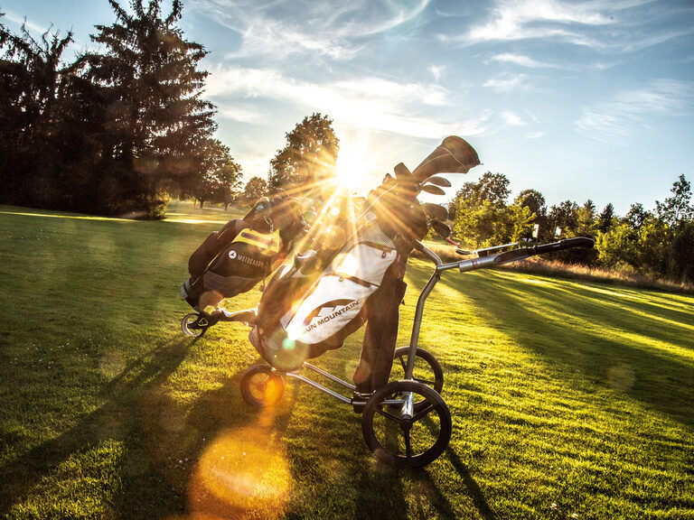 Ein Golfer zieht seinen Trolley über die gepflegte Golfanlage des Hotel Anetseder.
