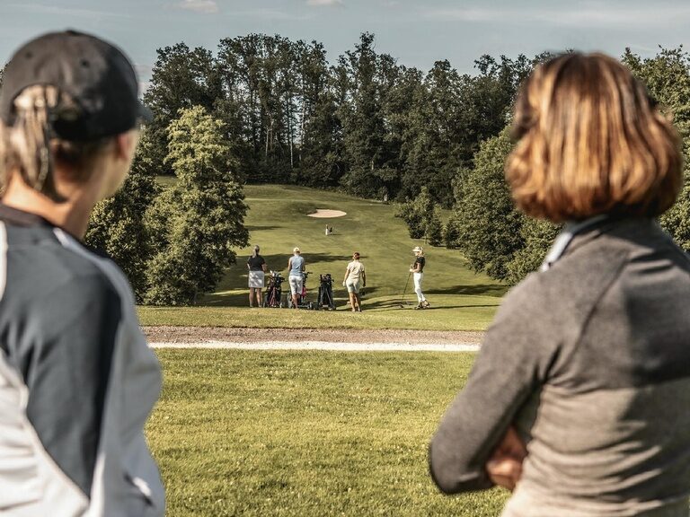 Mehrere aktive Gäste genießen ihre Zeit auf dem Golfplatz des Hotel Anetseder, umgeben von herrlicher Landschaft und frischer Luft.